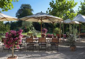 Romantik Hotel de L'Ours في Sugiez: مجموعة طاولات وكراسي مع مظلات وزهور