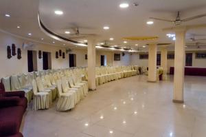 a room with rows of white chairs and tables at Central Hotel in Lucknow