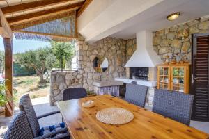 uma sala de jantar com uma mesa de madeira e uma parede de pedra em 2 bedrooms house at Martinscica 50 m away from the beach with furnished garden and wifi em Martinšćica