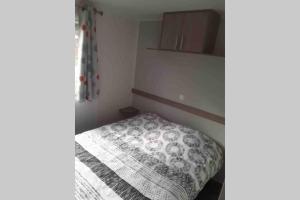 Dormitorio pequeño con cama con edredón en Mobil-Home 6 personnes à Munster en Alsace, en Munster