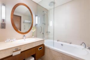 a bathroom with a sink, mirror, and bathtub at Crowne Plaza Doha - The Business Park, an IHG Hotel in Doha
