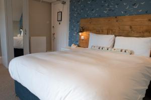 a bedroom with a large white bed with a blue wall at The Randolph Hotel in Southwold