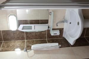 a bathroom with a sink and a urinal and towels at Özhan Hotel in Antalya