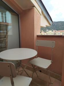 uma mesa e duas cadeiras num quarto com uma janela em La mansarda della luna em Pietra Ligure