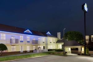 a large yellow building with blue lights on it at Days Inn & Suites by Wyndham DFW Airport South-Euless in Euless