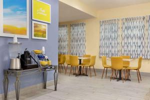 a dining room with yellow chairs and a table at Days Inn & Suites by Wyndham DFW Airport South-Euless in Euless