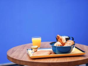 uma bandeja com uma tigela de pão e um copo de sumo de laranja em ibis Styles Perpignan Centre Gare em Perpignan