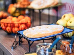 ein blaues Tablett mit einem Brot auf einem Tisch mit Obst in der Unterkunft ibis Styles Perpignan Centre Gare in Perpignan