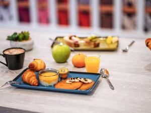 einen Teller mit Lebensmitteln auf einem Tisch mit Orangensaft in der Unterkunft ibis Styles Perpignan Centre Gare in Perpignan