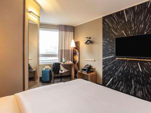 um quarto de hotel com uma cama e uma televisão de ecrã plano em ibis Heidelberg Hauptbahnhof em Heidelberg