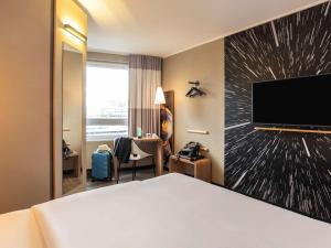 Cette chambre comprend un lit et une télévision à écran plat. dans l'établissement ibis Heidelberg Hauptbahnhof, à Heidelberg