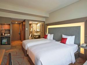 a large hotel room with two beds with red pillows at Novotel Kolkata Hotel and Residences in Kolkata