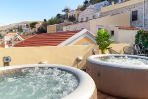 bañera de hidromasaje en el balcón de un edificio en Maravelia's Rooms, en Symi