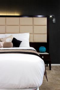 a bedroom with a large white bed with a large headboard at VR Queen Street Hotel & Suites in Auckland