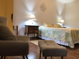 a bedroom with two beds and a chair and a table at Tiradentes Pousada Ramalhete in Tiradentes