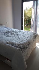 a bed with a white comforter in front of a window at Mimosas in Andernos-les-Bains