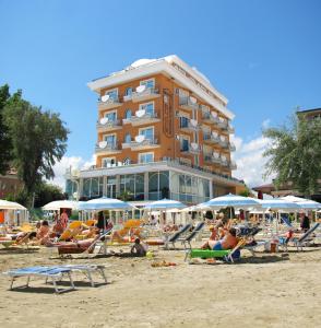 a group of people sitting on the beach in front of a hotel at El Cid Campeador - Family Hotel in Rimini