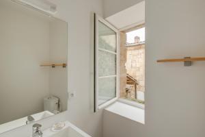 a white bathroom with a window and a sink at Logis Andraud Studios in Saint-Émilion