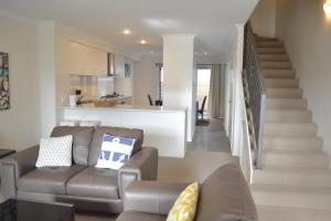 a living room with a couch and a staircase at North Coogee Beach House in Fremantle