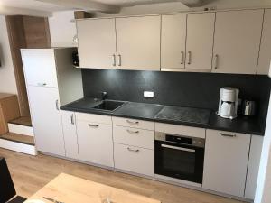 a kitchen with white cabinets and a sink at Haus Echtler in Hopferau