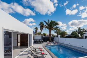 a patio with a swimming pool and chairs next to a house at Villa Rossa - Villas Now - LH215 By Villas Now Ltd in Playa Blanca +40 photos
