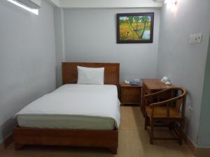 a bedroom with a bed and a table and a desk at Khách sạn Phú An in Cà Mau