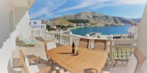 a wooden table on a balcony with a view of the water at Apartments Niko Metajna, island Pag in Metajna