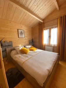 ein Schlafzimmer mit einem großen Bett in einem Holzzimmer in der Unterkunft Les Chalets Du Marais in Saint-Pierre-Aigle