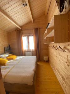 ein Schlafzimmer mit einem Bett in einer Holzhütte in der Unterkunft Les Chalets Du Marais in Saint-Pierre-Aigle