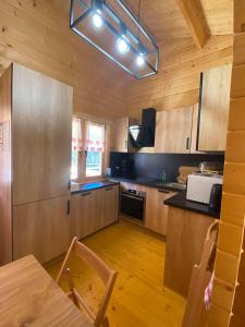 eine Küche mit Holzschränken und einem Tisch mit Stühlen in der Unterkunft Les Chalets Du Marais in Saint-Pierre-Aigle