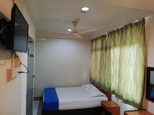 um pequeno quarto com uma cama e uma televisão em Sri Gate Hotel em Dungun