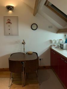 Una cocina con una mesa y un reloj en la pared. en Dove Cottage (Annex), en Workington 14 fotos más