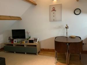 a living room with a table and a desk with a clock at Dove Cottage (Annex) in Workington