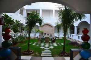 un patio con palmeras, mesa y sillas en Brahma Paradise , A heritage haveli, en Pushkar