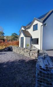 ein weißes Haus mit einer Steinmauer davor in der Unterkunft Yr Hen Berllan in the Beautiful Rowen in Conwy