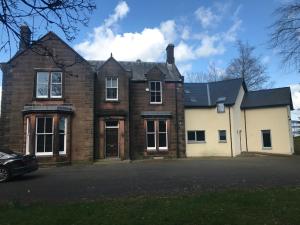 uma velha casa de tijolos com um carro estacionado em frente em Stewart Hall em Dumfries