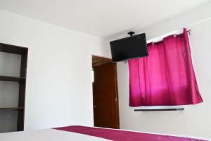 a bedroom with a red curtain and a tv at Motel Moon in Puebla