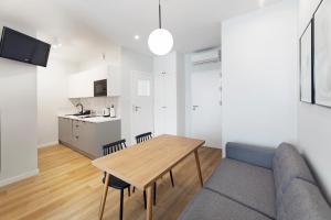 a living room with a table and chairs and a kitchen at Apartamenty Familijne przy parku klimatyzacja parking in Kudowa-Zdrój