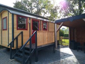 een tiny house met rode deuren en een veranda bij Langs De Maas in Boxmeer