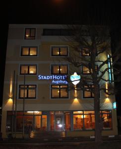 um edifício com um sinal para um hotel de estrelas à noite em Stadthotel Augsburg em Augsburg