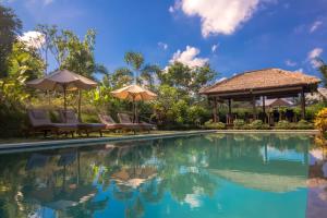 a pool at a resort with chairs and umbrellas at Villa Shantiasa Bali in Sidemen