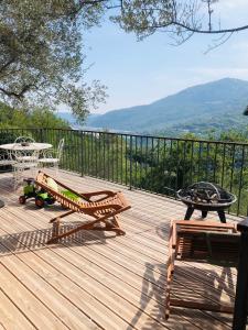 a wooden deck with a grill and a table and chairs at Cabane de L Esteron in Gilette