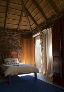 a bedroom with a bed and a stone wall at Griffons Bush Camp in Thabazimbi