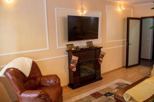 a living room with a television and a chair and a fireplace at APARTAMENT ALESSI BUȘTENI in Buşteni