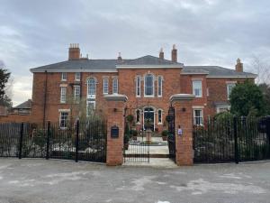 uma grande casa de tijolos vermelhos com uma cerca preta em The Dower House Apartments em Lincoln