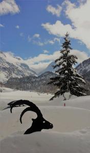 a statue of a goat in the snow next to a tree at Maloja Kulm Hotel in Maloja