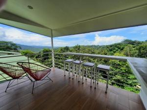 a balcony with chairs and a view of the forest at Rancho Capulin B&B in Tárcoles