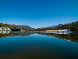 ein großer Wasserkörper mit Bergen im Hintergrund in der Unterkunft Novotel Lake Crackenback Resort in Crackenback