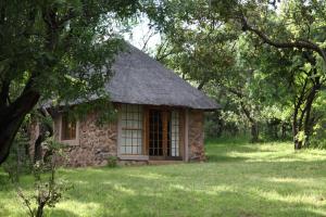 ein kleines Steingebäude mit Grasdach in der Unterkunft Griffons Bush Camp in Thabazimbi