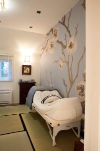 una camera ospedaliera con un letto e un murale sull'albero di Wabi Sabi B&B a Peer